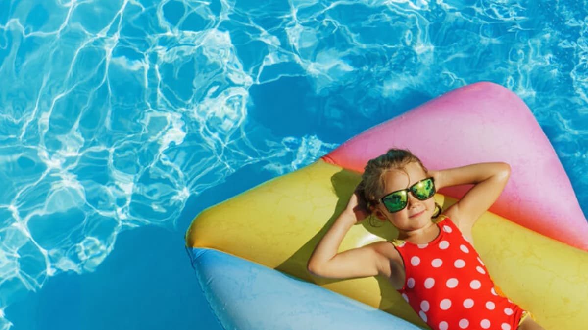 A happy child relaxing on a float in a clean, sparkling SPS PoolCare pool